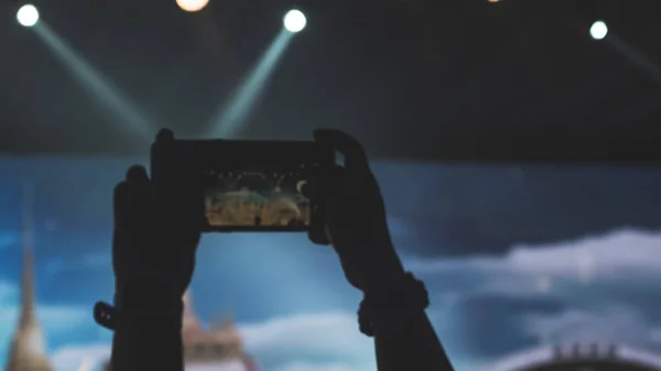 People holding their smart phones and photographing concert . Capture video at a concert at the phone camera in a bright spotlight lamps