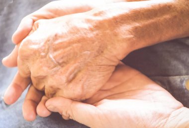 Yaşlı ve genç bir kadın el ele tutuşuyor. İnsanlar, bakım ve destek. El konseptine yardım etmek. Yaşlılara bakım ve yardım kavramı, yaşlı ve genç insanların arasındaki bağ..