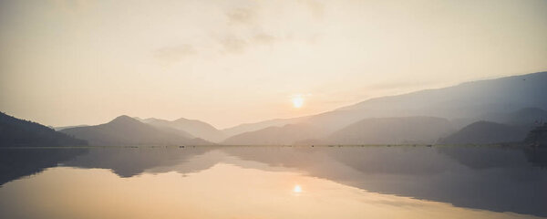 Гора, небо и река в тихой и прохладной атмосфере. Похожая цветовая гамма. Вид на голубые горы с отражением в озере. Пейзаж с голубыми горами возле озера в Сукхотай Таиланд
