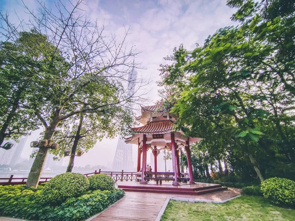 The Canton Tower formally Guangzhou TV Astronomical and Sightseeing. Viewed from the front entrance of Park with traditional Chinese Pavilion. New and old architecture in frame.