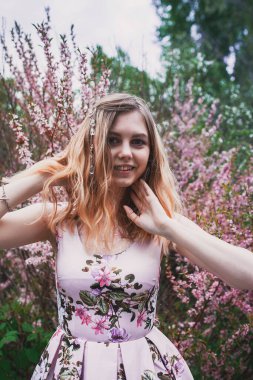 Üzerinde mehendi olan narin elbiseli bir kız, çiçek açmış bademler içinde.