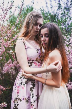 Üzerinde mehendi olan narin elbiseli bir kız, çiçek açmış bademler içinde.