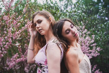 Üzerinde mehendi olan narin elbiseli bir kız, çiçek açmış bademler içinde.