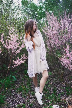 Üzerinde mehendi olan narin elbiseli bir kız, çiçek açmış bademler içinde.