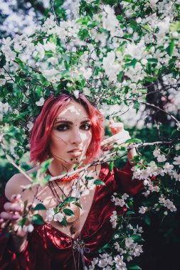 Kırmızı saçlı ve elma ağaçlarındaki Druid şeklinde bir kız.