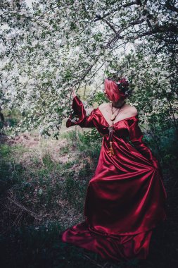 Kırmızı saçlı ve elma ağaçlarındaki Druid şeklinde bir kız.