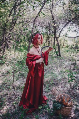 Kırmızı saçlı ve elma ağaçlarındaki Druid şeklinde bir kız.