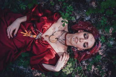 Kırmızı saçlı ve elma ağaçlarındaki Druid şeklinde bir kız.