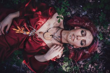 Kırmızı saçlı ve elma ağaçlarındaki Druid şeklinde bir kız.