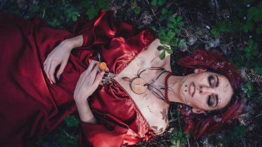 Kırmızı saçlı ve elma ağaçlarındaki Druid şeklinde bir kız.
