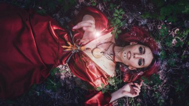 Kırmızı saçlı ve elma ağaçlarındaki Druid şeklinde bir kız.