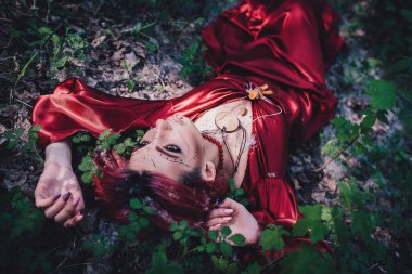 Kırmızı saçlı ve elma ağaçlarındaki Druid şeklinde bir kız.