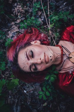 Kırmızı saçlı ve elma ağaçlarındaki Druid şeklinde bir kız.