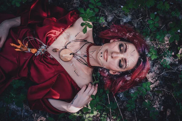 Kırmızı saçlı ve elma ağaçlarındaki Druid şeklinde bir kız.
