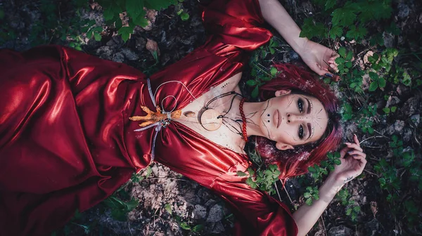 Kırmızı saçlı ve elma ağaçlarındaki Druid şeklinde bir kız.