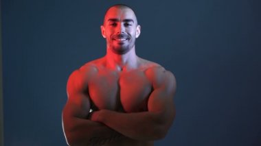 Mutlu, pozitif vücut geliştiricinin stüdyo fotoğraf çekiminde göğüs kaslarını esnetirkenki yakın görüntüsü