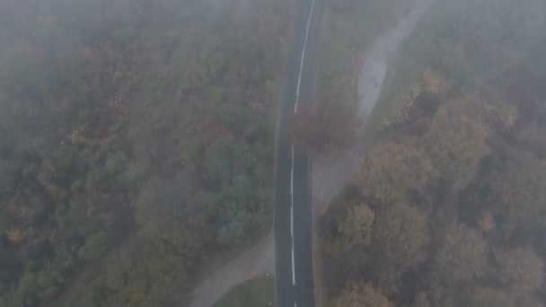 Drohne verfolgt weißes Auto auf dunkler und nebliger Bergstraße — Stockvideo