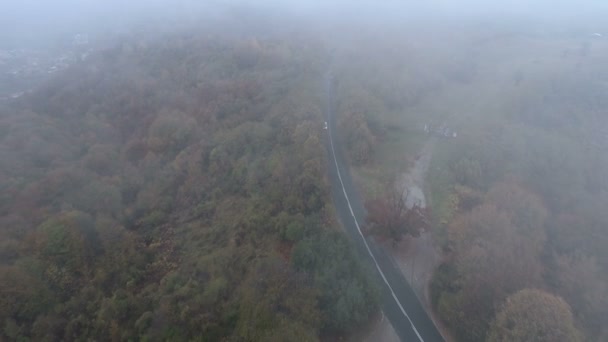 秋に霧の多い山道を白い車で走るドローン — ストック動画