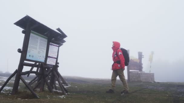 Turista ztracený v mlze v červené bundě na vrcholu hory — Stock video
