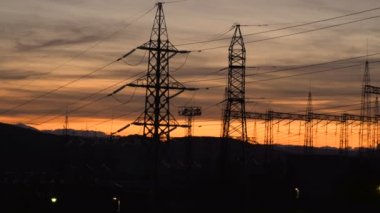 Yüksek voltajlı elektrik kulesinin siluetleri gün batımında ve günbatımında bulutlu gökyüzünde
