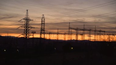 Gün batımında yüksek voltajlı elektrik hatları. Elektrik dağıtım istasyonu