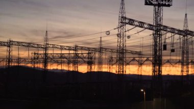 Turuncu günbatımı gökyüzünde elektrik direği, çevresel hasar. Sarı turuncu günbatımına karşı elektrik direkleri