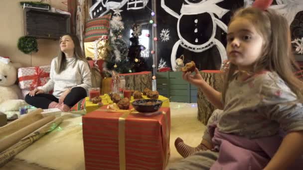 Радостная беременная мама и ее ребенок слушают рождественские колядки, истории сидят рядом с подарками — стоковое видео