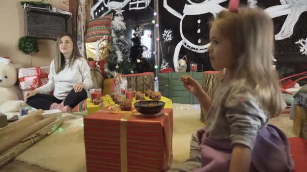 Prachtig blond meisje dat dineert op kerstavond. Zwangere moeder zitten op de grond tijd doorbrengen met haar kind — Stockvideo