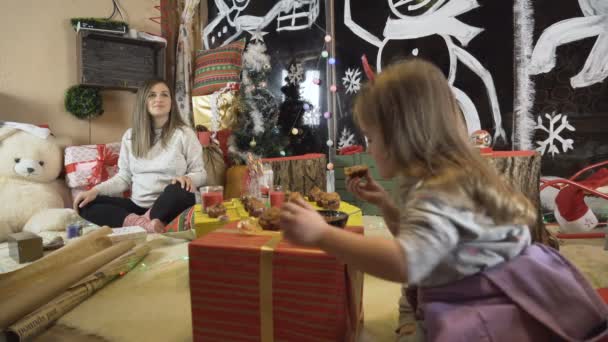 Zwangere moeder en haar dochter genieten van kerstavond samen met vele kerstverlichting — Stockvideo