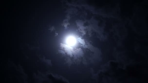 Full moon at night with bright and dark clouds passing, covering the moon — Stock Video