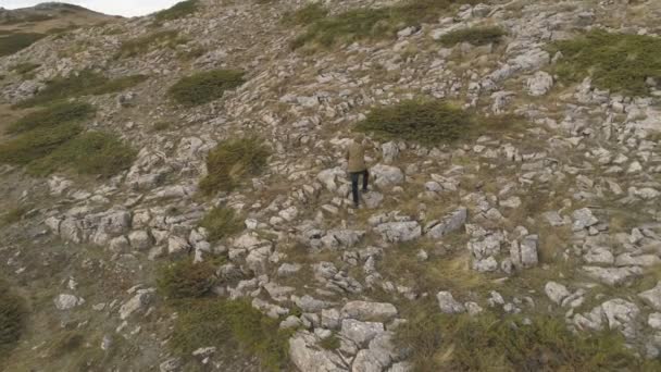 Mann touristische Wanderung auf scharfen Felsen Gipfel. Einsame Wanderer in grüner Jacke genießen Aussicht. — Stockvideo