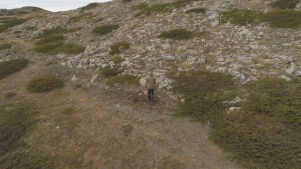 Путешественник поход в одиночку на скалистом холме, уверенно наслаждаясь праздником — стоковое видео