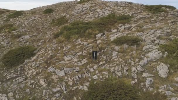 Un joven senderismo solo en un pico de montaña, vista hacia atrás — Vídeos de Stock