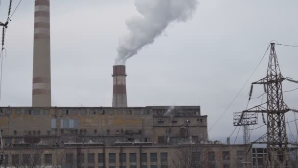 Огромные трубы крупного металлургического завода курят белый дым в туманный зимний день — стоковое видео
