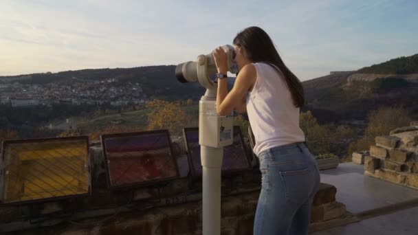 Feminino turista, menina morena com camisa branca assistindo a vista panorâmica com binocular. Tsarevets, Veliko Tarnovo — Vídeo de Stock