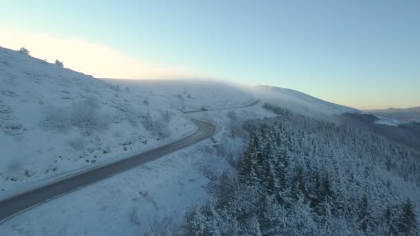 Під час снігового дня вантажні автомобілі повільно їздять гірською автострадою з величним видом на Болгарію. — стокове відео