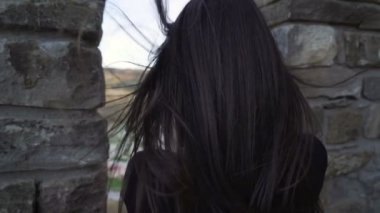 Esmer kız ortaçağ kalesinin duvarlarını izliyor ve akıllı telefonuyla fotoğraf çekiyor.