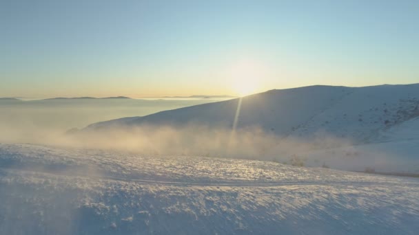 Mlha plovoucí nad horskými kopci pokrytá čerstvým sněhem, panoramatický výhled na západ slunce — Stock video