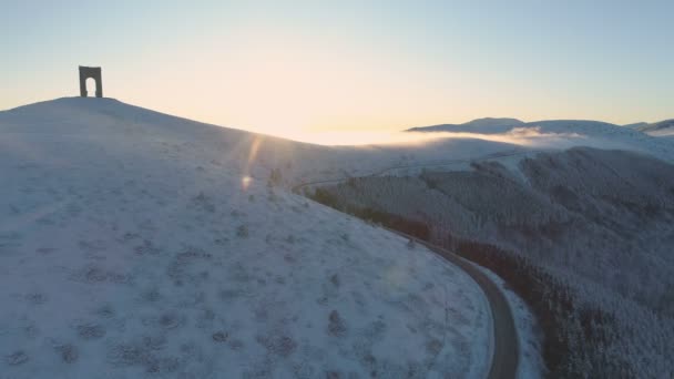 Letecký pohled na susnet přes zasněžené mlhavé hory s kluzkou horskou klikatou cestou — Stock video