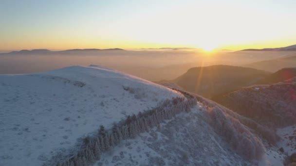 Vista aérea dos raios de sol do por do sol brilhando na estrada sinuosa da montanha e picos cobertos de neve — Vídeo de Stock