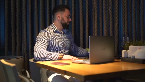 Eleganter Geschäftsmann mit teurer Uhr, der am Laptop arbeitet, während er zum Abendessen im Restaurant ist — Stockvideo