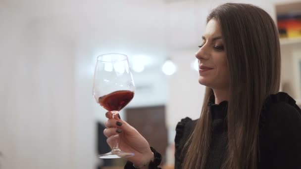 Žena ve večerních černých šatech ochutnávka červené víno na vánoční koktejl party — Stock video