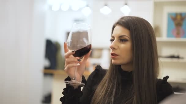 Ung, lycklig kvinna skakar och dricker glas rött vin sitter hemma — Stockvideo