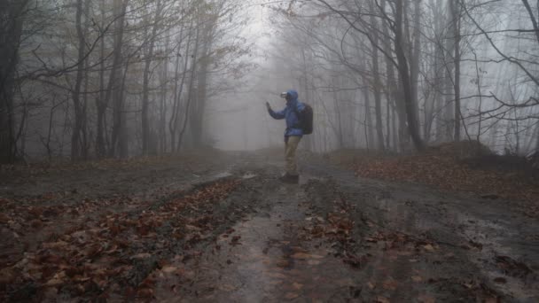 Man playing game with VR glasses outdoors in misty rainy forest, wandering around — Stock Video