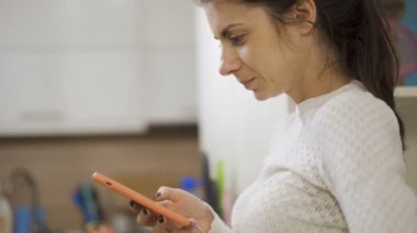 Brunnete girl concentrated using her phone while sitting in her house