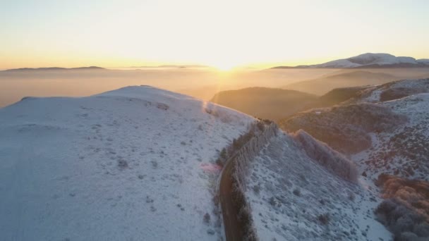 Letecký pohled na horský průsmyk asfaltovou cestou při západu slunce v zimní pohádkové krajině — Stock video