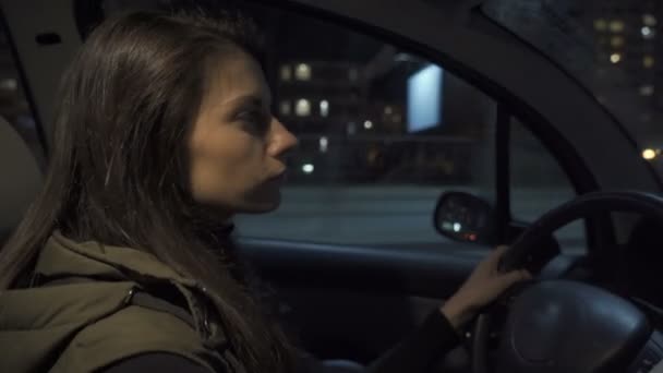 Wanita muda cantik mengendarai mobil di malam hari mendengarkan musik — Stok Video