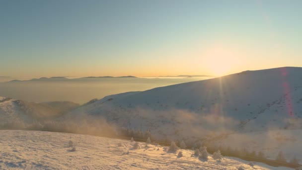 Sonnenaufgang auf nebelverhangenen, schneebedeckten Berggipfeln in heiterer Fernsicht — Stockvideo