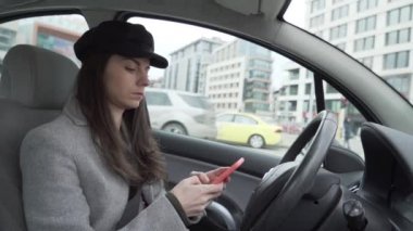Young woman with black hat using smartphone sitting on drivers seat