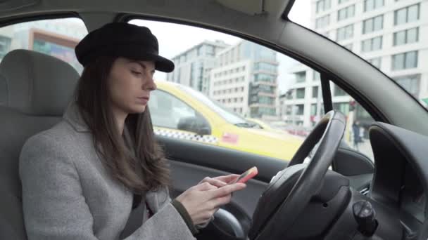 Girl using smartphone in car and checking rear view mirror — Stock Video